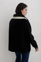 Camisa de paño de lana, color negro, con cuello tejido en contraste y cierre frontal de botones claros. Presenta bolsillos frontales y diseño de corte recto.
