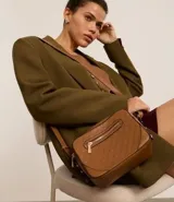 Bandolera pequeña color marrón con textura geométrica en relieve. Tiene correa ancha regulable, cierre de cremallera y separadores internos.