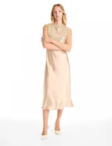 Vestido midi de satén color champagne con corte al bies y escote recto, acompañado por un top sin mangas de cuello alto cubierto de lentejuelas doradas con detalle drapeado en la cintura.
