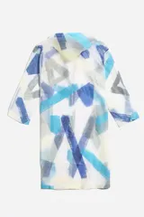 Piloto impermeable de corte recto y largo midi, con capucha ajustable mediante cordones. Presenta un diseño estampado con motivos botánicos en tonos verdes y amarillos sobre una base translúcida. Cuenta con cierre frontal mediante botones a presión y mangas largas.