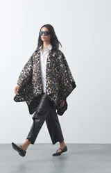 Poncho de silueta amplia con estampado animal print, bordes terminados con costura decorativa y diseño envolvente.