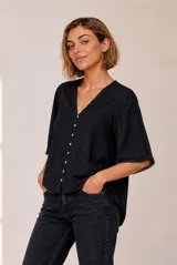 Camisa negra de manga corta con escote en V, cierre frontal de botones claros y detalles de encaje en las mangas.