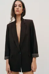 Blazer de lino color verde militar, con cuello solapa, hombreras y manga larga con puño revuelto con detalle a rayas. Cuenta con cierre frontal de un botón y bolsillos delanteros con solapa.