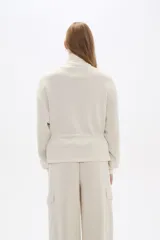 Campera de cuello alto con cierre frontal, bolsillos frontales con solapa y cordón ajustable en la cintura. Diseño de manga larga con puños elásticos.