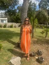 Vestido midi color naranja con rayas verticales blancas, de tejido de punto en hilo, con breteles anchos y corte recto.