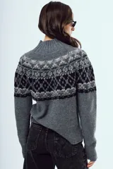 Sweater de punto color marrón, con cuello alto y diseño tejido con patrones geométricos en tonos negros y blancos en la parte superior y mangas.