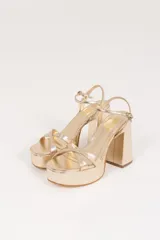 Sandalias de cuero sintético color manteca, con plataforma y tacón bloque. Presentan tiras cruzadas en el empeine y pulsera con hebilla al tobillo.