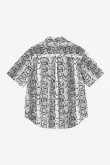 Camisa de manga corta con estampado animal print de serpiente en tonos grises y blancos, cuello camisero y cierre frontal con botones.
