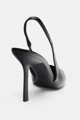 Zapato de tacón alto tipo stiletto, color negro, con diseño destalonado y tira elástica trasera. Presenta punta fina y tacón fino.