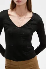 Remera negra de manga larga y calce al cuerpo, confeccionada en poliéster con diseño calado y escote en V.