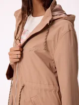 Rompevientos negro con capucha ajustable mediante cordones, cierre frontal de cremallera y ajuste en la cintura con cordón. Presenta logo de la marca bordado en el pecho y puños con detalle de botón.