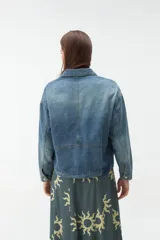 Campera de denim azul con bolsillos frontales con solapa, cuello clásico y cierre de botones metálicos.