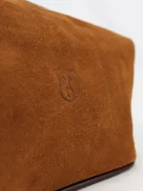 Neceser de cuero color mostaza con textura natural y logo grabado en el centro. Cuenta con cierre superior y diseño estructurado.