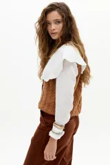 Chaleco de punto color caramelo con ochos en el frente, cuello a la base y terminaciones de rib.