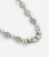 Cadena de metal plateado con eslabones ovalados calados que contienen una estrella de cinco puntas. Incluye dos cierres de mosquetón giratorios.