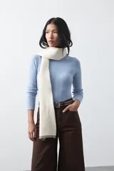 Polera de tejido de punto con textura calada y diseño de líneas verticales acanaladas. Presenta cuello alto y mangas largas con puños delicados, de silueta entallada.