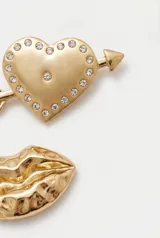 Pin metálico con diseño de labios dorados.