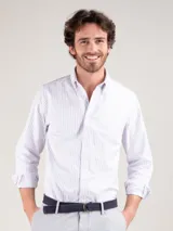 Camisa de hombre oxford con diseño de rayas verticales celestes y blancas, corte regular fit, cuello button-down, manga larga y cierre frontal con botones.