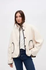 Campera de sherpa doble faz color bordó, con cierre frontal de botones, cuello alto y bolsillos laterales. Presenta detalles de vivos en nylon color tostado en los bordes y costuras.