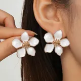 Par de caravanas con forma de flor blanca con centro dorado.