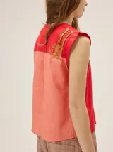 Remera sin mangas de diseño bicolor en tonos rojo y salmón, con detalles bordados en la espalda.