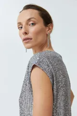 Vestido corto plateado con lentejuelas, escote en V y mangas cortas.