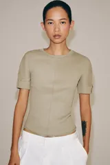 Camiseta de manga corta confeccionada en hilatura con mezcla de algodón, con diseño de tejido en rib y corte slim fit. Presenta cuello redondo y costuras verticales decorativas en el frente.