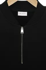 Sudadera de algodón color negro, con cuello redondo y cierre frontal parcial. Presenta mangas largas con puños y ruedo en rib.