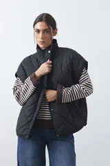 Chaleco acolchado de nylon con diseño capitoneado, cuello alto y cierre frontal con botones a presión. Presenta un calce amplio y versátil.