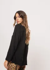 Camisa negra de cuello redondo con frunces y mangas largas con puños abiertos.