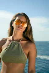 Top de bikini estilo halter con escote cerrado, confeccionado en tela de toalla color verde militar con ribetes en tono beige. Posee tiras ajustables en cuello y espalda.