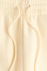 Pantalón deportivo de tiro alto confeccionado en felpa de mezcla de algodón con interior cepillado. Presenta cintura elástica con cordón de ajuste, bolsillos laterales al bies y puños elásticos en los bajos.