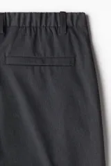 Pantalón de corte ajustado en color gris oscuro, con cierre frontal de botón, bolsillos laterales y bolsillo trasero insertado.