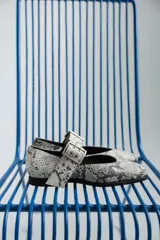 Chatas plateadas de cuero con punta cuadrada, tira sobre el empeine con hebilla metálica y suela plana.