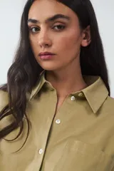 Vestido corto de algodón color beige, con diseño de camisa de manga larga en la parte superior y falda cruzada tipo pareo con bajo asimétrico y lazada lateral.