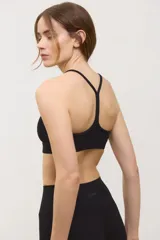 Top deportivo negro de compresión media, con escote redondo clásico, tiras finas cruzadas en la espalda y tazas intercambiables.