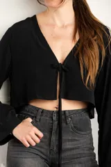 Blusa corta negra con escote en V y mangas largas acampanadas.
