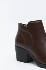Bota corta de cuero sintético color marrón oscuro, con diseño minimalista, puntera afinada y taco ancho de altura media.