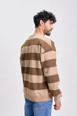 Buzo deportivo de cuello redondo, color beige con rayas horizontales marrones. Tiene mangas largas y puños y dobladillo acanalados.