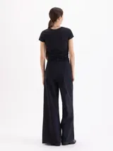 Pantalón de corte ancho y silueta relajada, confeccionado en tejido técnico con elasticidad. Presenta recortes verticales en el frente que terminan en aberturas en el ruedo y cuenta con un cinturón integrado con hebilla metálica de enganche.