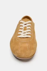Zapatilla deportiva de piel en color marrón tostado, con diseño de perfil bajo, detalles de pespuntes y cierre mediante cordones.