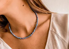 Collar corto de cuentas de vidrio en tonos celeste y azul, con pequeñas cuentas plateadas.