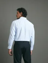 Camisa de vestir de manga larga en color celeste, con cuello clásico, cierre frontal de botones y bolsillo en el pecho.