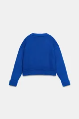 Jersey de punto color azul eléctrico con escote en pico, manga larga y detalle de costuras marcadas en los hombros. Presenta un corte ligeramente cropped con puños y ruedo acanalados.