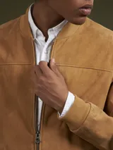 Campera bomber color camel de gamuza, con cierre frontal y bolsillos laterales.