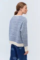 Sweater color crudo con jacquard floreado en lurex negro y puños con textura delicada.