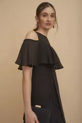 Vestido largo negro con hombros descubiertos, volados en el pecho, mangas cortas y paneles de encaje transparente en la falda.