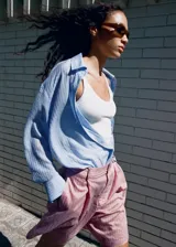 Camisa de manga larga con diseño a rayas en tonos celestes y blancos, cuello camisero y cierre frontal con botones.