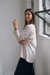 Remera de algodón color beige, con cuello en V, mangas largas con costuras caídas y ruedo con detalle de costura horizontal.