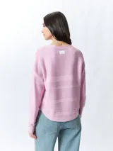 Mochila pequeña color rosa pálido con correas ajustables y asa superior. Tiene un bolsillo frontal con cierre y un parche con el logo de la marca en la parte inferior.